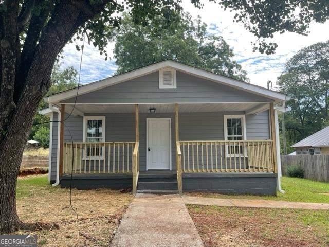 bungalow-style home featuring covered porch and a front yard