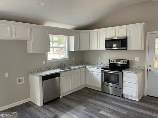 kitchen featuring white cabinets, lofted ceiling, stainless steel appliances, sink, and light stone counters