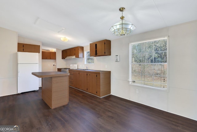 kitchen with lofted ceiling, pendant lighting, a kitchen island, white appliances, and dark wood-type flooring