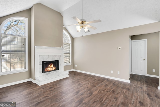 unfurnished living room with ceiling fan, vaulted ceiling, a premium fireplace, a textured ceiling, and dark hardwood / wood-style flooring