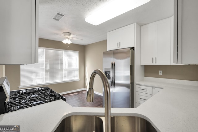 kitchen with ceiling fan, sink, white cabinetry, stainless steel appliances, and a textured ceiling