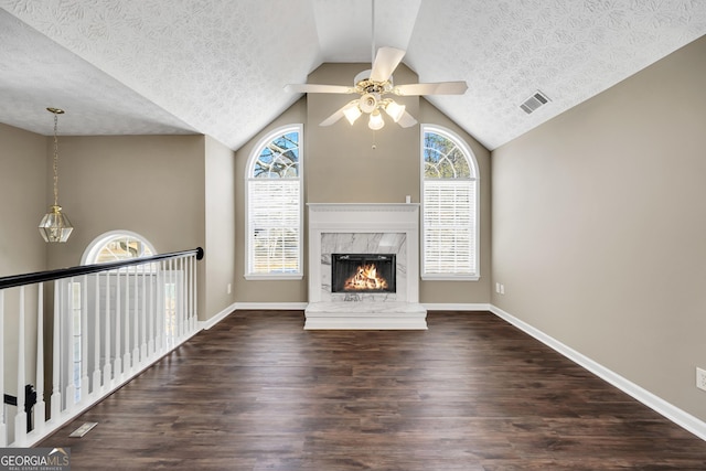 unfurnished living room with ceiling fan, vaulted ceiling, a premium fireplace, a textured ceiling, and dark hardwood / wood-style flooring