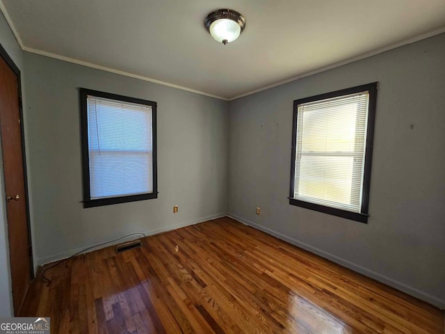 empty room featuring hardwood / wood-style flooring and crown molding