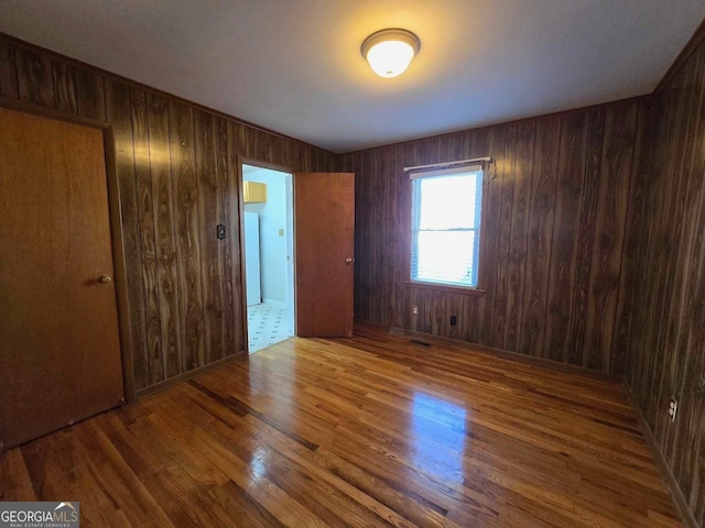 unfurnished room featuring wood-type flooring and wood walls