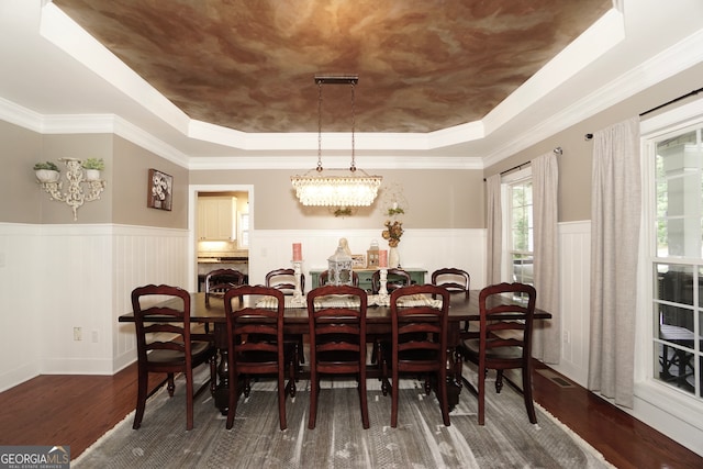 dining space featuring dark hardwood / wood-style flooring, ornamental molding, and a raised ceiling