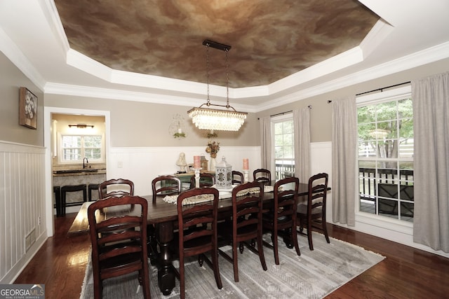 dining area with dark wood-type flooring, ornamental molding, and a tray ceiling