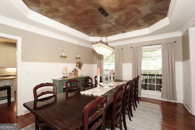 dining area featuring dark wood-type flooring, ornamental molding, and a tray ceiling