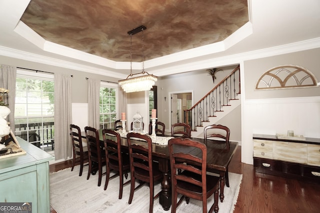 dining area featuring hardwood / wood-style flooring, crown molding, and a raised ceiling