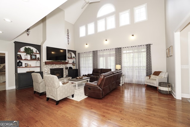 living room featuring a fireplace, a towering ceiling, and hardwood / wood-style floors