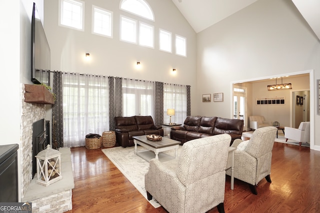 living room featuring high vaulted ceiling, plenty of natural light, a stone fireplace, and dark hardwood / wood-style floors