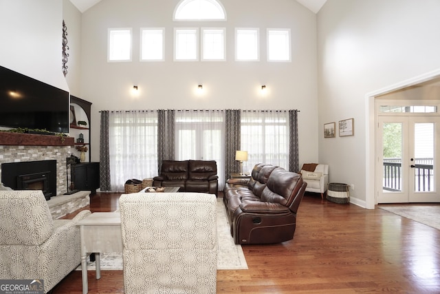 living room featuring a high ceiling, wood-type flooring, a fireplace, and french doors