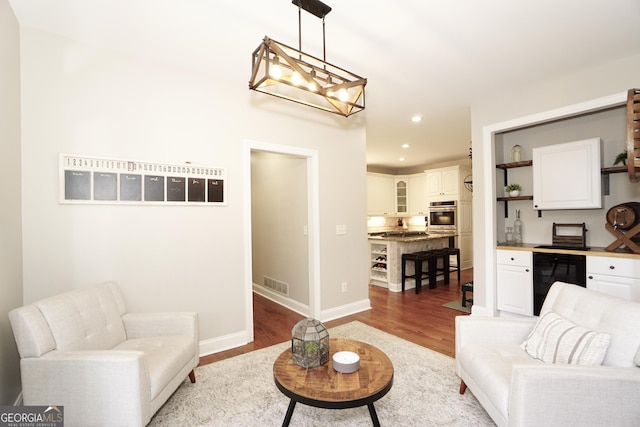 living room featuring wine cooler, light wood-type flooring, and a chandelier