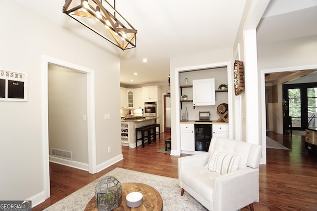 living room with wine cooler, dark wood-type flooring, and a chandelier