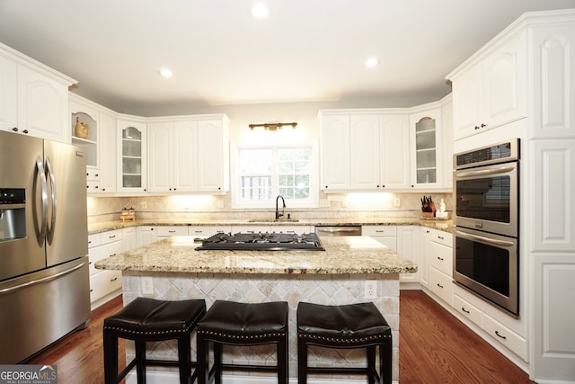 kitchen featuring stainless steel appliances, white cabinetry, a kitchen island, and sink