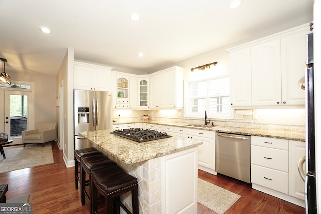 kitchen with white cabinets, appliances with stainless steel finishes, sink, and a center island