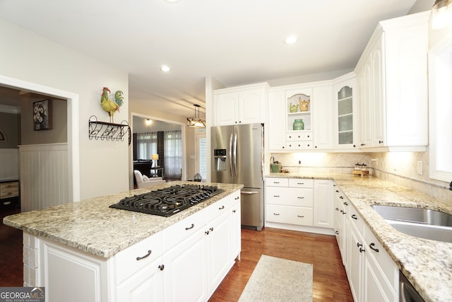 kitchen featuring light stone counters, a kitchen island, stainless steel appliances, and white cabinetry