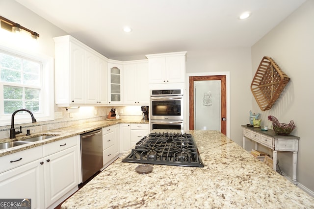 kitchen featuring light stone countertops, sink, white cabinetry, and appliances with stainless steel finishes