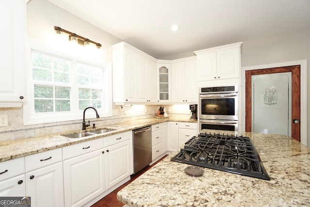 kitchen featuring light stone countertops, appliances with stainless steel finishes, sink, and white cabinetry