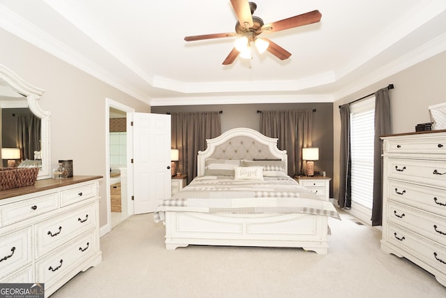 bedroom featuring ceiling fan, light colored carpet, a tray ceiling, and ensuite bath