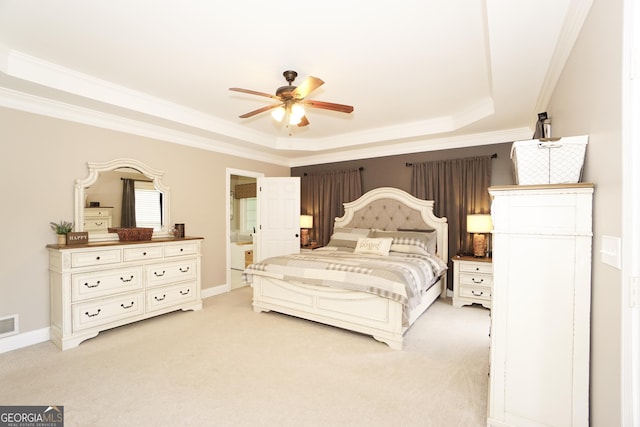 bedroom featuring ceiling fan, ensuite bathroom, light colored carpet, and a raised ceiling