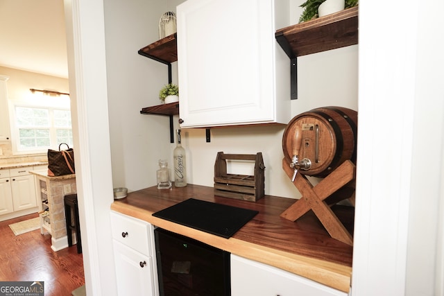 bar with dark wood-type flooring, white cabinetry, and beverage cooler