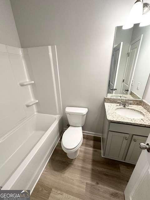 full bathroom featuring bathtub / shower combination, wood-type flooring, toilet, and vanity