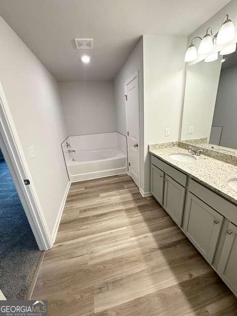 bathroom featuring hardwood / wood-style floors, a tub to relax in, and vanity