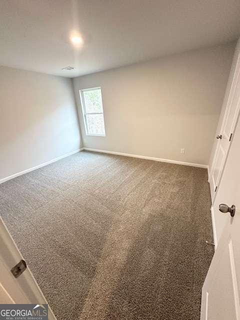 unfurnished room featuring dark colored carpet