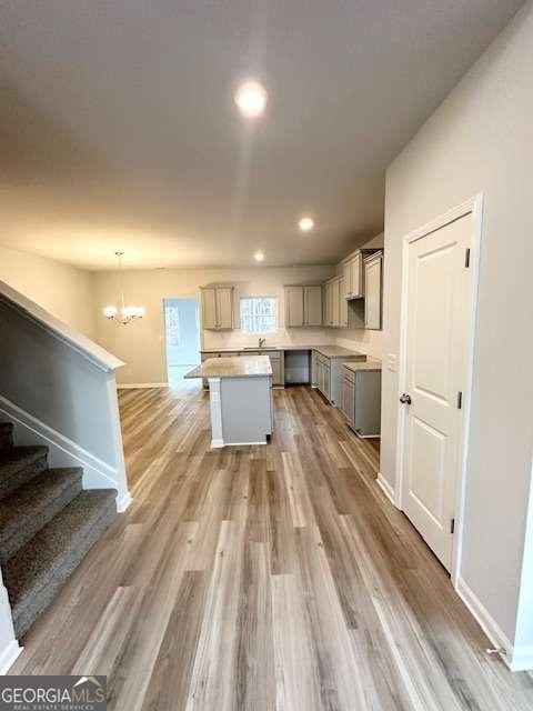 kitchen with decorative light fixtures, a center island, wood-type flooring, gray cabinetry, and a chandelier