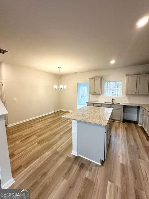 kitchen featuring dark wood-type flooring, gray cabinetry, pendant lighting, and a center island