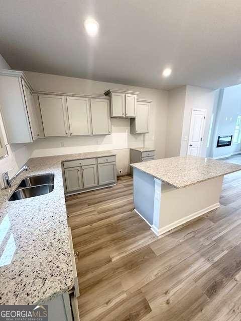 kitchen with sink, light stone counters, and a center island