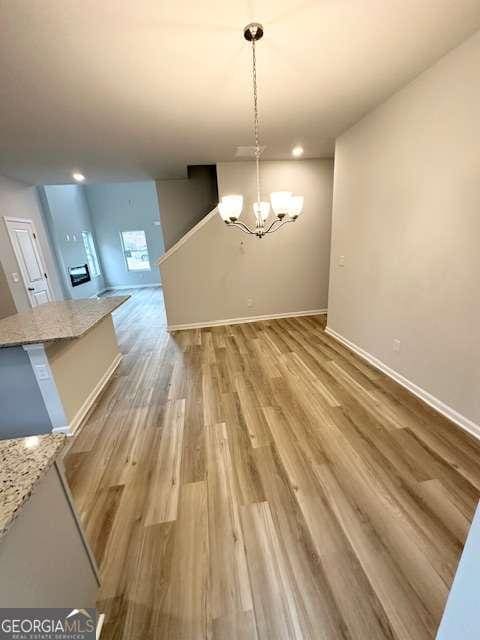 unfurnished dining area with hardwood / wood-style floors and a notable chandelier