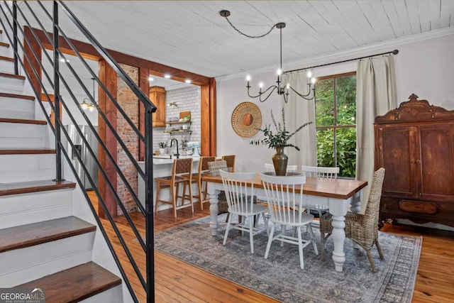 dining area with an inviting chandelier, hardwood / wood-style floors, wood ceiling, and ornamental molding