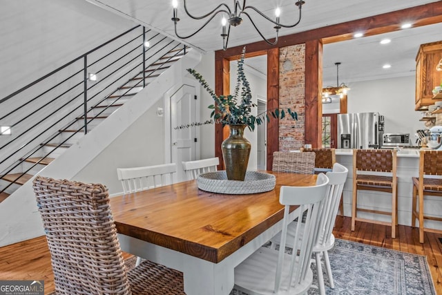 dining space with crown molding, wood-type flooring, and a notable chandelier