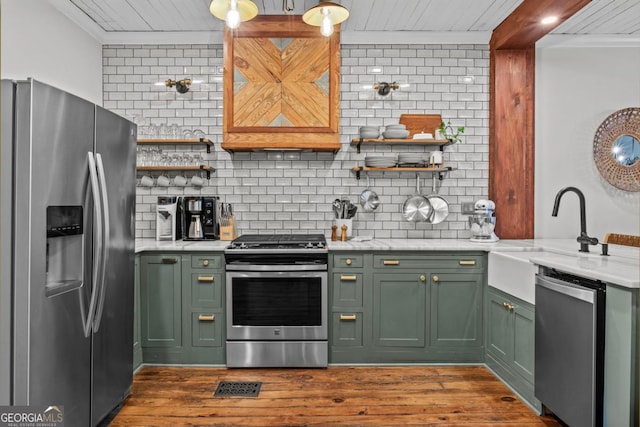 kitchen featuring dark wood-type flooring, sink, appliances with stainless steel finishes, green cabinets, and decorative backsplash