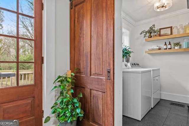 washroom with dark tile patterned floors, ornamental molding, a barn door, and washing machine and clothes dryer