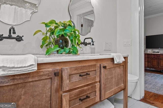 bathroom with tile patterned floors, ornamental molding, toilet, and vanity