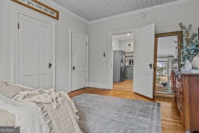 bedroom featuring light hardwood / wood-style flooring, stainless steel fridge, ornamental molding, and a closet