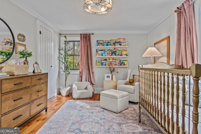 bedroom featuring hardwood / wood-style floors, a crib, and ornamental molding