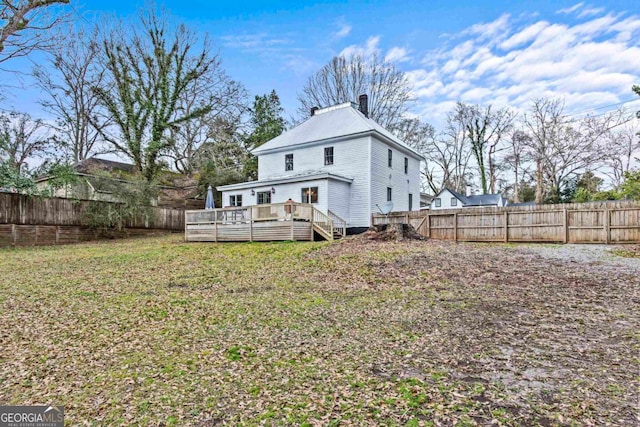 back of property with a wooden deck and a lawn