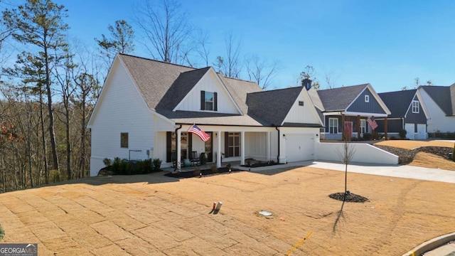 modern inspired farmhouse with roof with shingles, covered porch, a chimney, driveway, and an attached garage