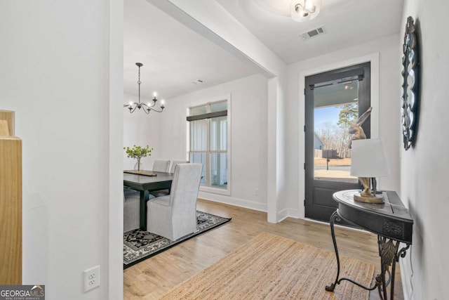 foyer featuring visible vents, baseboards, wood finished floors, and a chandelier