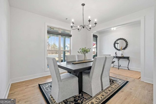 dining space featuring a notable chandelier, wood finished floors, and baseboards