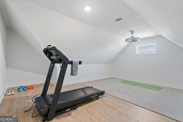 exercise area featuring vaulted ceiling, wood finished floors, visible vents, and baseboards