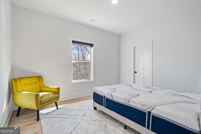 bedroom with light wood finished floors, visible vents, and baseboards