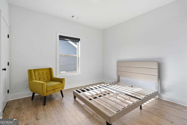 bedroom with visible vents, baseboards, and wood finished floors