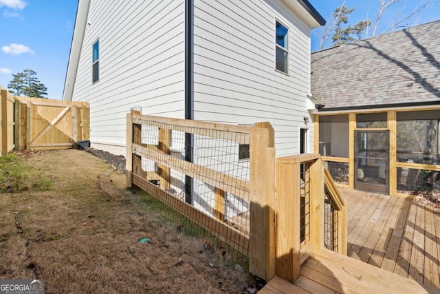 view of property exterior featuring a gate, a wooden deck, roof with shingles, and fence