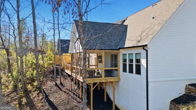 back of property with a wooden deck, brick siding, and a shingled roof