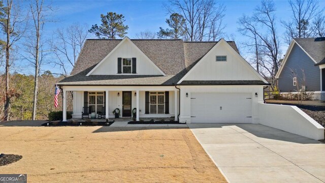 modern farmhouse with a porch, driveway, an attached garage, and a shingled roof