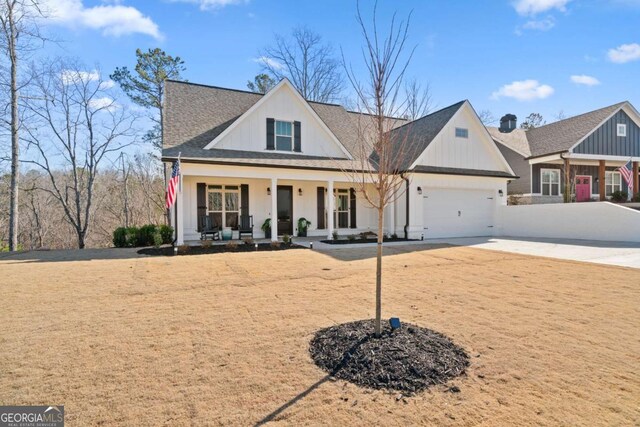 modern inspired farmhouse with a porch, concrete driveway, an attached garage, and roof with shingles